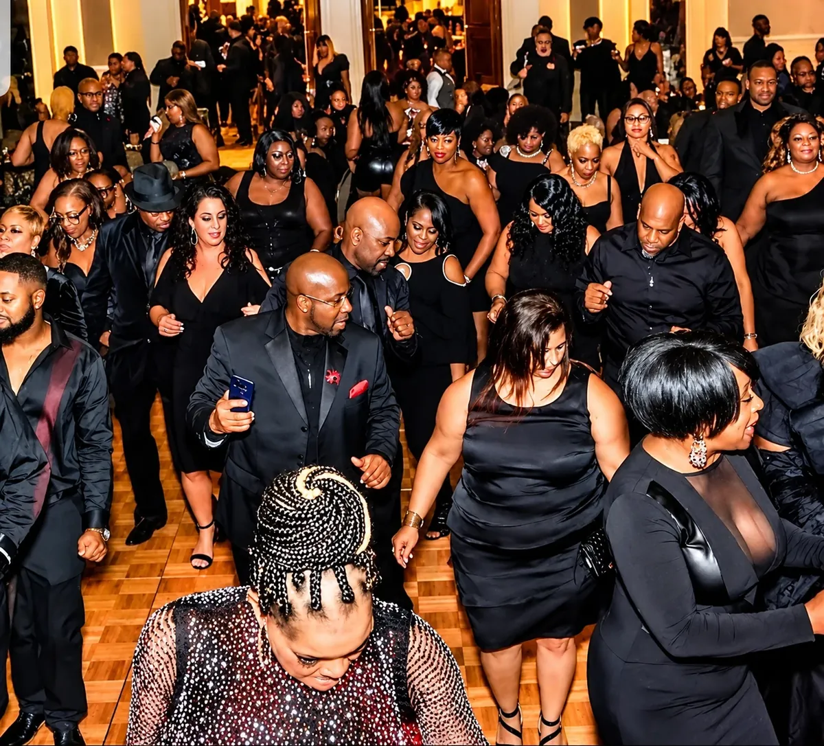 Guests dressed in black celebrating on a crowded ballroom dance floor