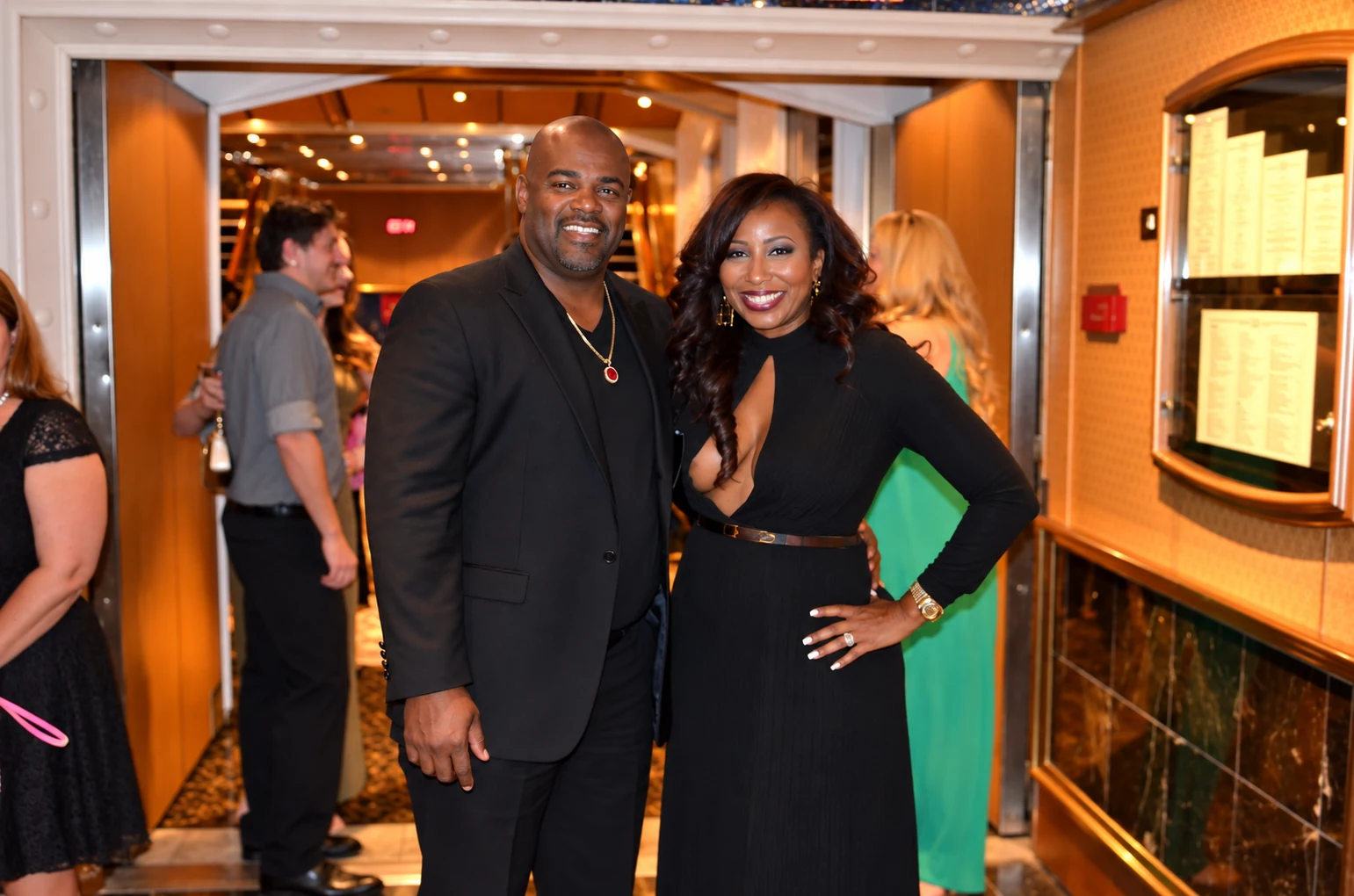 Couple dressed in black formal attire smiling at a cruise dining room entrance
