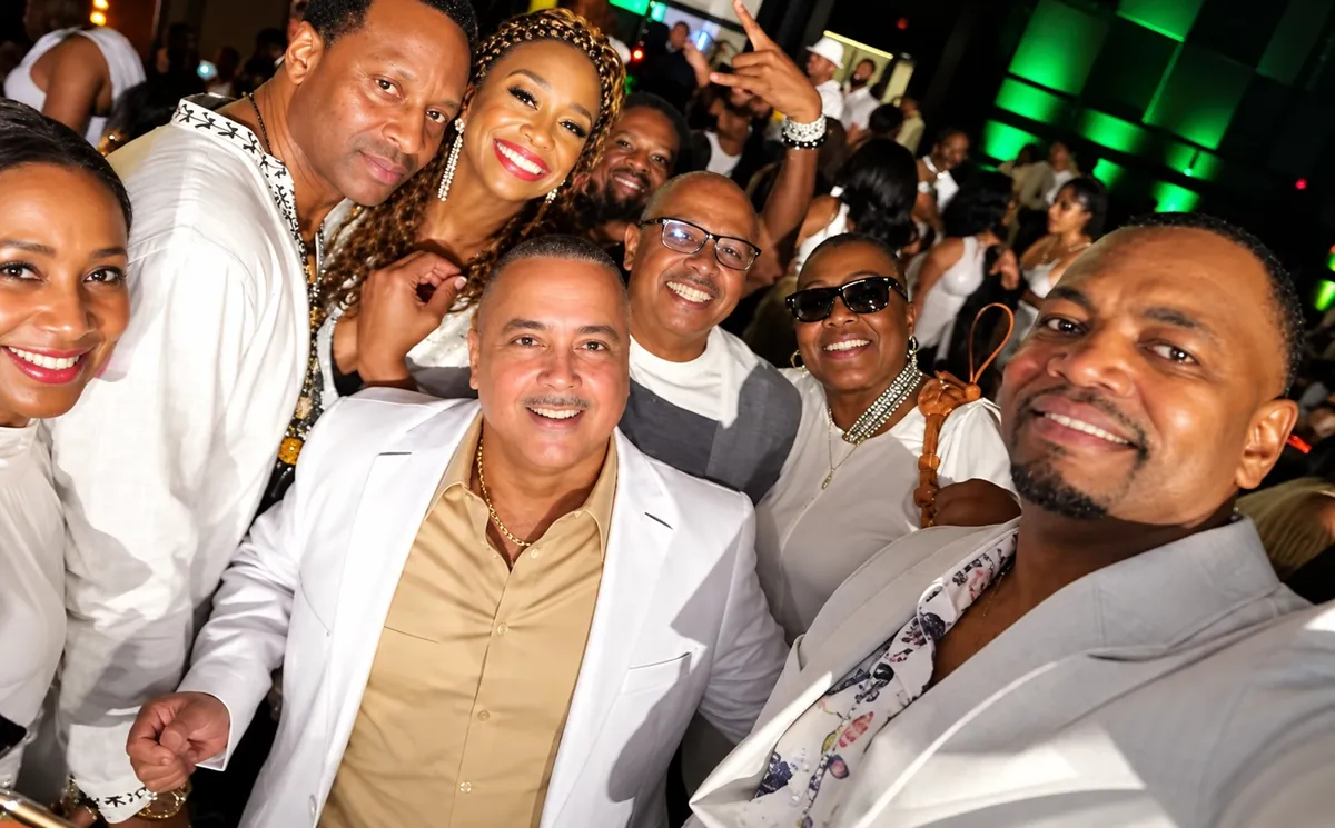 Friends dressed in white smiling for a group selfie at a party